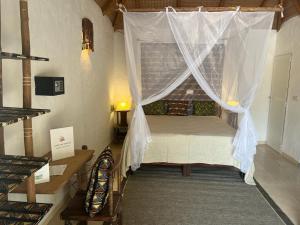 a bedroom with a bed with a mosquito net at Keur Papaye in Dinouar