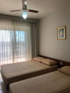 a bedroom with two beds and a ceiling fan at Atlântico Sul Renascença Hotel in Laguna