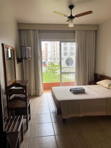 a bedroom with a bed and a chair and a window at Atlântico Sul Renascença Hotel in Laguna