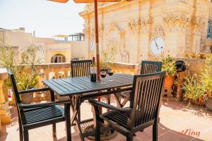 stół i krzesła na patio z zegarem w obiekcie A pretty apartment in a Gozo village square w mieście Victoria