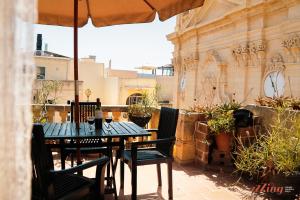 stół i krzesła na patio z parasolem w obiekcie A pretty apartment in a Gozo village square w mieście Victoria