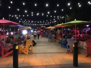 un grupo de personas sentadas bajo sombrillas en un patio por la noche en Ocean Flats 3 - Lauderdale-by-the-Sea, en Fort Lauderdale
