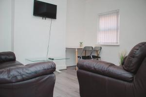 a living room with two leather chairs and a television at Nicely made relaxing 4 Bedroom near LFC Stadium in Liverpool