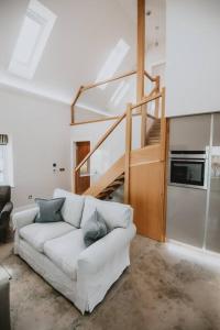 een woonkamer met een witte bank en een trap bij The Bothy at Aikenshill in Aberdeen