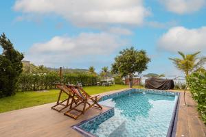 uma piscina com duas cadeiras e uma mesa em Casa Na Praia em Angra dos Reis em Angra dos Reis