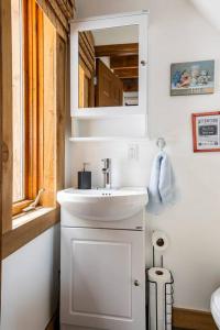 Baño blanco con lavabo y espejo en Charming Cottage In a Peaceful Forest & Calm River, en Sainte Béatrix