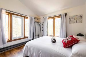 1 dormitorio con 1 cama blanca con almohadas y ventanas de color rojo en Charming Cottage In a Peaceful Forest & Calm River, en Sainte Béatrix