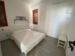 een witte slaapkamer met een bed en een stoel bij Casa di Giu' - favignana in Favignana