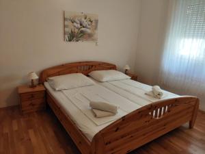 a bedroom with a wooden bed with white sheets and pillows at Villa Niko in Podstrana