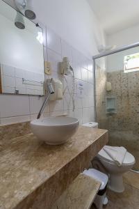 La salle de bains est pourvue d'un lavabo et de toilettes. dans l'établissement Pousada Pé na Estrada, à Arraial d'Ajuda