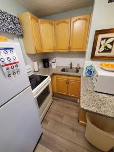 a kitchen with wooden cabinets and a white refrigerator at The Floranada Condo at Pompano Beach 9 in Pompano Beach