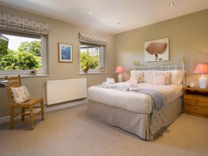 a bedroom with a bed and a chair and two windows at Mere View in Windermere