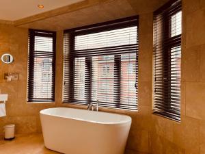 eine große Badewanne im Bad mit Fenstern in der Unterkunft Gatsby Hotel - Adults Only - Small Luxury Hotel - by F-Hotels in Blankenberge