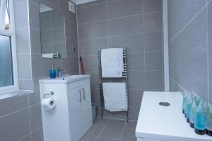 ein Badezimmer mit einem Waschbecken, einem WC und einem Spiegel in der Unterkunft Evergreen Apartments-Flat 4, London in London