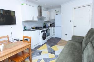 a living room with a couch and a kitchen at Evergreen Apartments-Flat 4, London in London