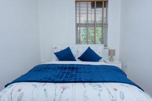 a bedroom with a blue and white bed with blue pillows at Evergreen Apartments-Flat 4, London in London