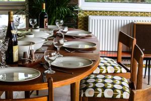 una mesa de madera con platos y copas de vino. en Pant Golau - The Seventies House, en Llanbedr