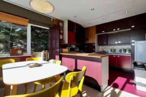 a kitchen with a white table and yellow chairs at Pant Golau - The Seventies House in Llanbedr