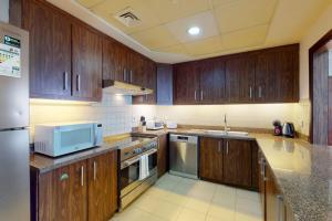 a kitchen with wooden cabinets and a microwave at West Heights 2 - Vacationer in Dubai