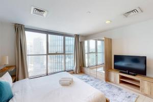 a bedroom with a large bed with a television and large windows at West Heights 2 - Vacationer in Dubai