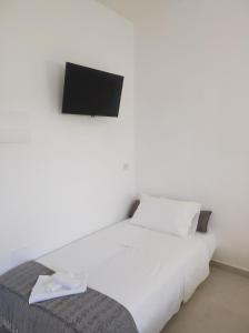 uma cama branca com uma televisão na parede em B&B Spiaggia Le Dune em Margherita di Savoia