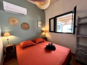 a bedroom with a red bed and a window at Kaz'Ban, 2ème ligne, 40 m du lagon in Saint-Leu