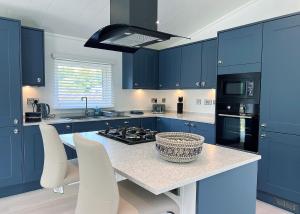 a kitchen with blue cabinets and a table with white chairs at Bowland Escapes in Chipping