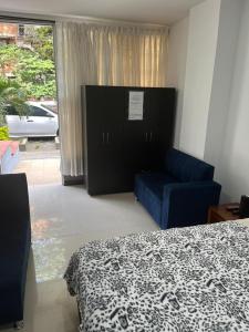 - une chambre avec un lit et un canapé bleu dans l'établissement Apartaestudio cerca a Plaza Mayor, à Medellín