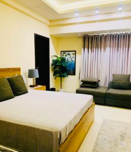 a bedroom with a large bed and a couch at Elysium Service Apartment 1203 in Islamabad