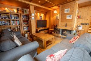 ein Wohnzimmer mit Sofas, einem TV und einem Kamin in der Unterkunft Chalet Clearmount with Spa in Méribel