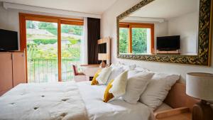 een slaapkamer met een groot wit bed en een spiegel bij Hôtel Real Nyon by HappyCulture in Nyon