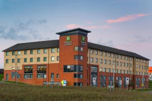 a large red brick building with a black roof at Holiday Inn Express London Luton Airport, an IHG Hotel in Luton