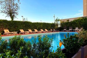 a swimming pool with chaise lounges and lounge chairs at Hotel Granada in Milano Marittima