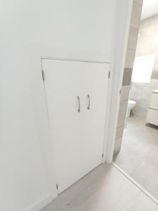 a white bathroom with a door in a room at Entresuelo luminoso cerca de Escaño in Ferrol