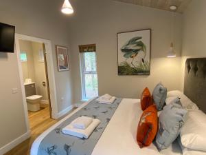 um quarto com uma grande cama branca com almofadas laranja em Conker Lodge with Hot Tub em Cupar