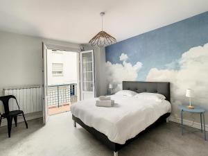 een slaapkamer met een groot bed met wolken op de muur bij Foncillon Plage in Royan