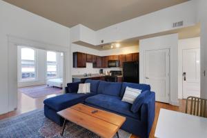 a living room with a blue couch and a kitchen at Historic Guthrie Coke Lofts, Downtown Louisville in Louisville