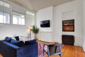 a living room with a blue couch and a tv at Historic Charm In Guthrie Coke Lofts in Louisville