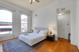 a white bedroom with a bed and two windows at Historic Charm In Guthrie Coke Lofts in Louisville