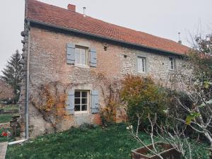 MarignyにあるCharmant Gite 4 Places dans le Juraの青いシャッターが付いた古いレンガ造りの家