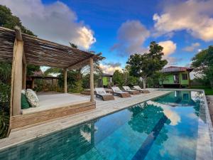 a pool with chairs and a gazebo next to a house at Villa Prana Trancoso - Vista mar in Trancoso