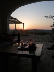 a table with a plate of food on it with the sunset at Narasha Homestay - Maasai Mara in Talek