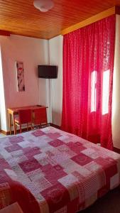 パッシーにあるHOTEL Le TOURISMEのベッドルーム1室(ベッド1台、赤いカーテン、デスク付)