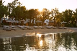 a park with umbrellas and a body of water at Minos Beach Art Hotel, a Member of Design Hotels in Agios Nikolaos