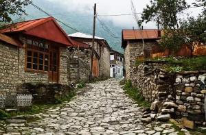 a cobblestone street next to two stone buildings at Lahij Rashad Ismayilov Hotel in Lahıc