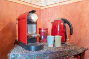 uma máquina de café vermelha e chávenas numa mesa em Atelier chez Marie em Carnetin