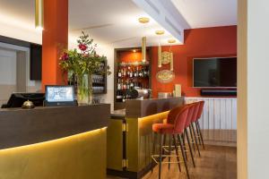 a bar with orange walls and orange stools at EMICH´S Hotel in Amorbach