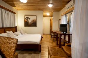 a hotel room with a bed and a desk and a television at Esther's Hotel in Accra