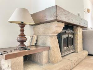 a lamp sitting on a table next to a stone fireplace at LA VILLA STE ANNE - Wifi - Plages et bourg de Plonevez à 2 min in Plonévez-Porzay