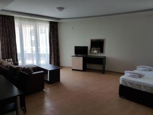 a hotel room with a bed and a couch and a tv at Sinemorets Cliffs in Sinemorets +13 photos